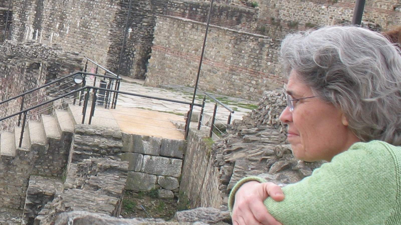 Woman looking out over stone ruins from a terrace abroad